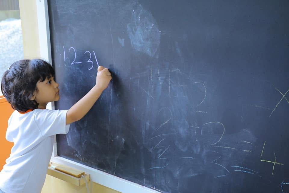 Child writing numbers on a chalkboard